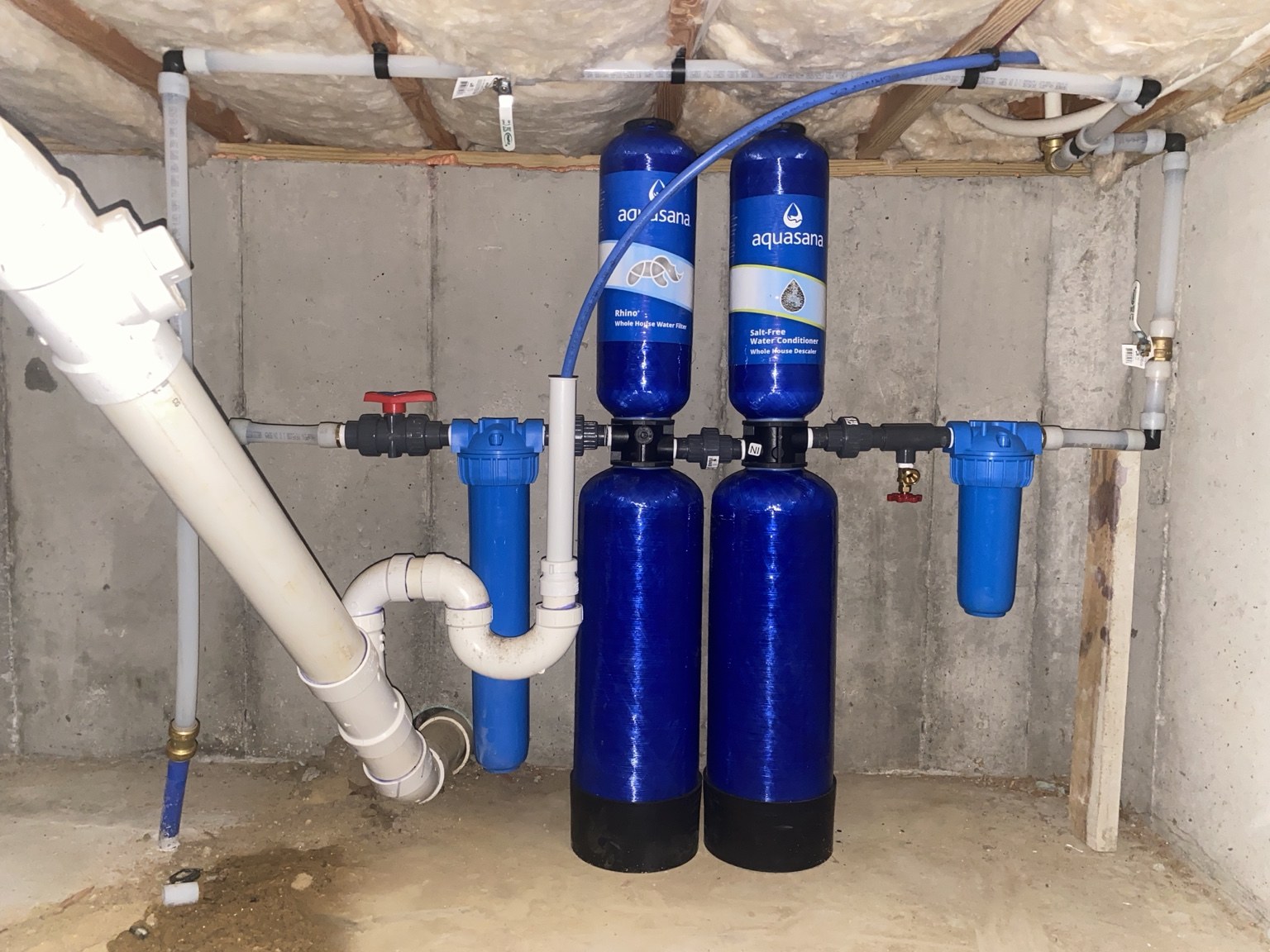 Original photograph of the installed Aquasana whole-home water filtration and salt-free conditioning system in the crawl space